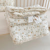 A stack of white floral muslin baby blankets with delicate embroidery and lace trim.