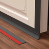 A door draft stopper with a red and gray strip is shown installed under a door frame on a wooden floor.