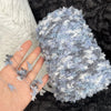 A hand is holding a ball of light blue and gray variegated yarn for knitting or crochet.