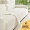 A cream anti-slip sofa cover is shown draped over a light-colored sofa, highlighting its textured, quilted surface.