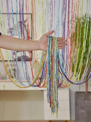A hand is holding a long, colorful tassel string curtain made of multicolored threads.