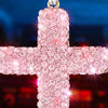 Pink rhinestone cross pendant hanging from a white loop.