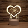 A glowing heart shape made of wireframe light illuminates two hands clasped together on a wooden surface.