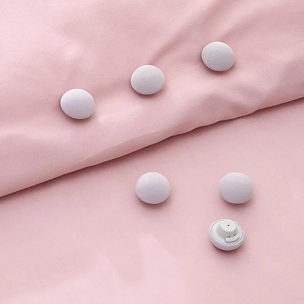 Six round white non-slip clips are arranged on a soft pink fabric surface.