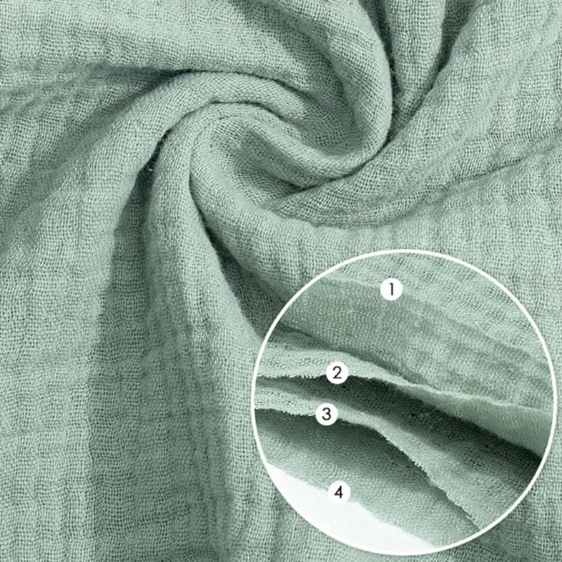 Close-up view of soft sage green cotton gauze fabric showing texture and folds.