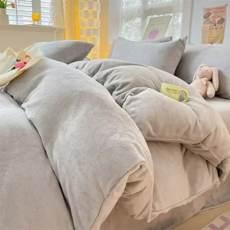 A close-up of a cozy milk velvet bedding set featuring a duvet cover and several soft gray pillows on a bed.