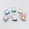 A collection of various clear and colored invisible hem shortening clips for pants shown on a white background.