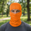 A man wearing an orange stretchy breathable balaclava cap covering his face in an outdoor setting.