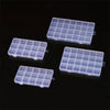 Four transparent multi-compartment storage boxes with fixed dividers arranged on a dark surface.
