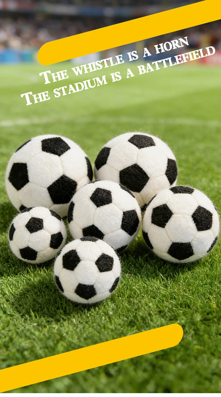 A pile of realistic black and white football plush toys resting on green grass.