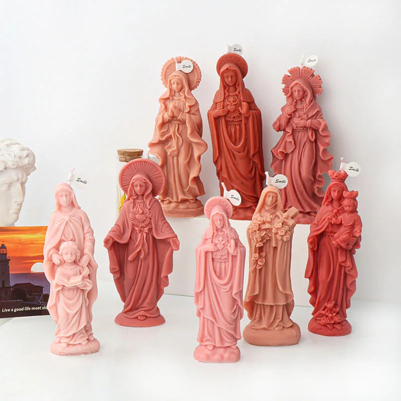 A collection of pink and reddish-orange 3D silicone molds depicting various religious figures for candle and resin crafting.