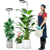 A woman holds a potted houseplant under a full spectrum LED grow light with a timer and adjustable stand.