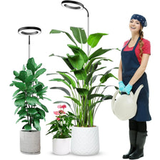 A woman holds a potted houseplant under a full spectrum LED grow light with a timer and adjustable stand.
