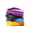 A stack of colorful reusable microfiber cleaning cloths in purple, gray, and blue.