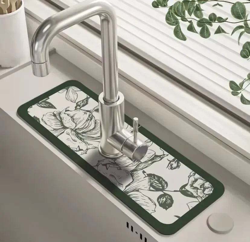 A modern chrome faucet mounted on a dark green floral patterned mat in a kitchen sink.