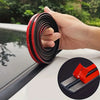 A hand is holding a black rubber seal strip with red accents, demonstrating the T-shaped product for car windshield gap prote