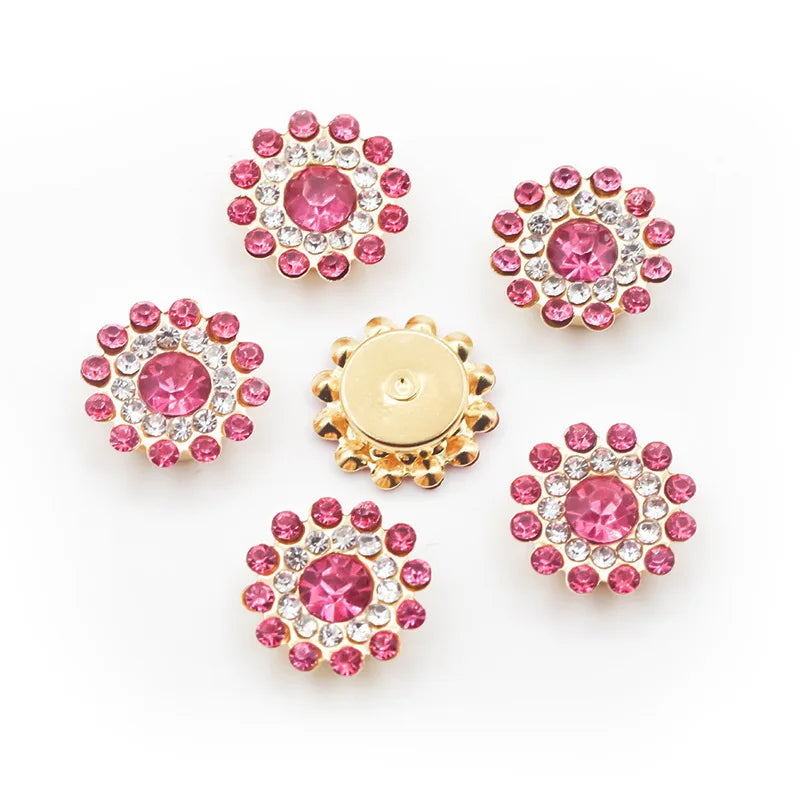 A collection of pink and clear rhinestone flowers, some set in gold-toned metal, arranged on a white background.
