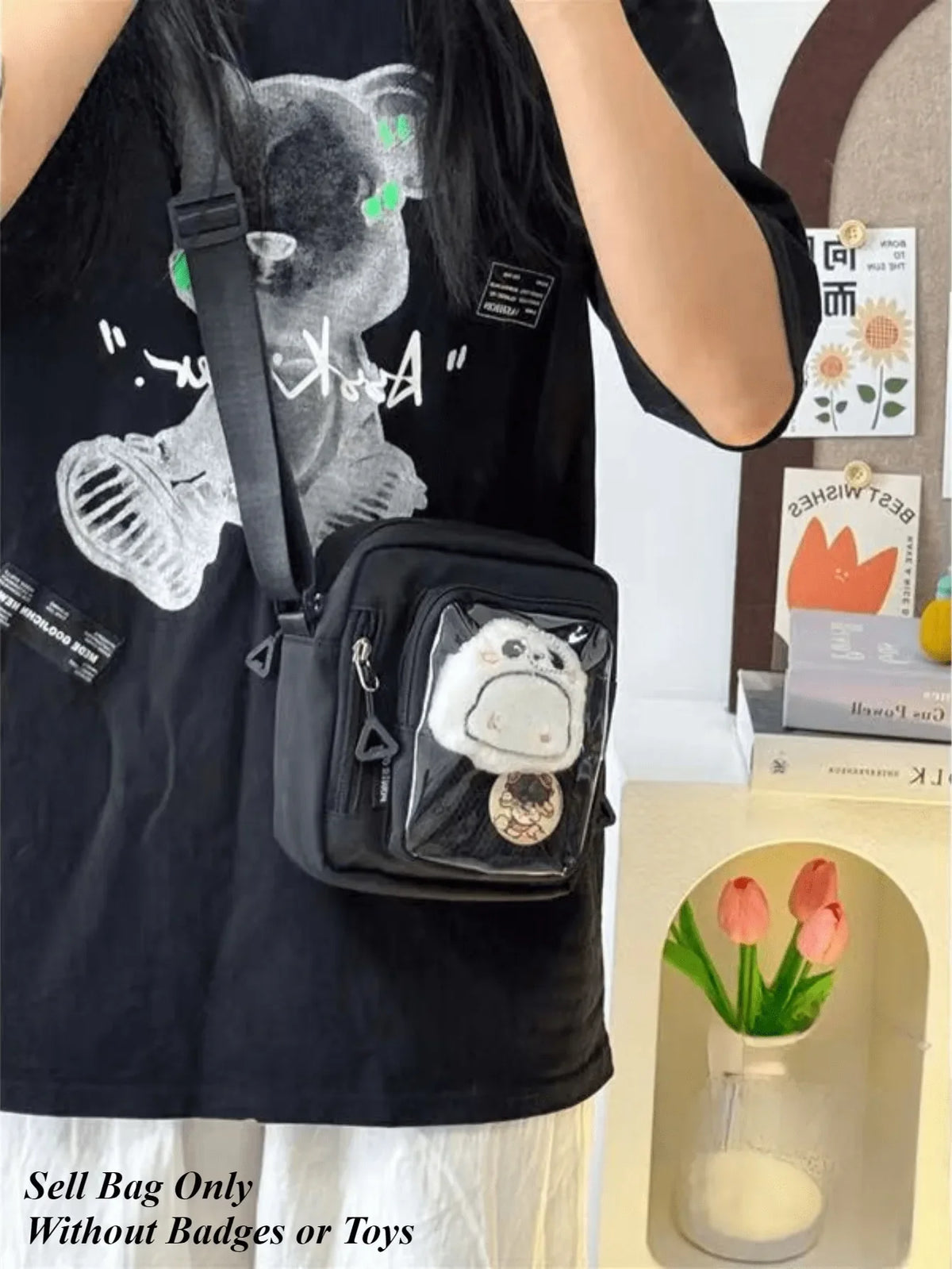 Camiseta negra con gráfico de oso y un pequeño bolso cruz negro con un dije blanco.