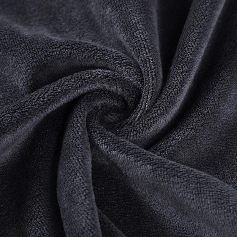 A dark gray microfiber bath towel is tightly rolled, showing its soft texture and absorbency.
