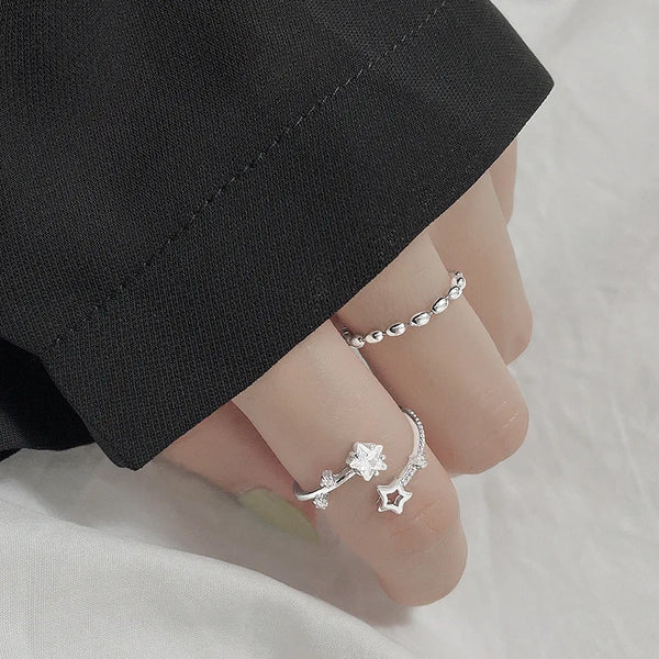Una mano vistiendo un anillo de estrella de plata esterlina ajustable contra un fondo blanco.