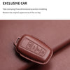 A brown leather key case cover is shown resting on a reddish-brown fabric surface.