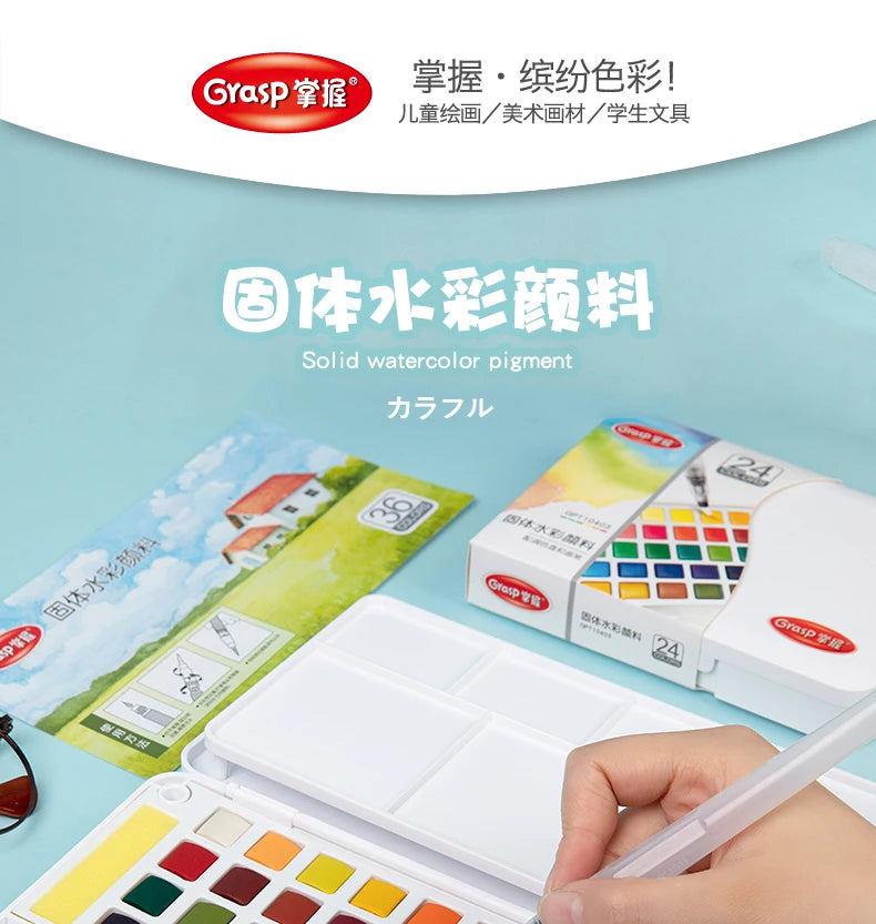 A box set of solid watercolor pigment paints and brushes is shown next to a palette on a light blue background.