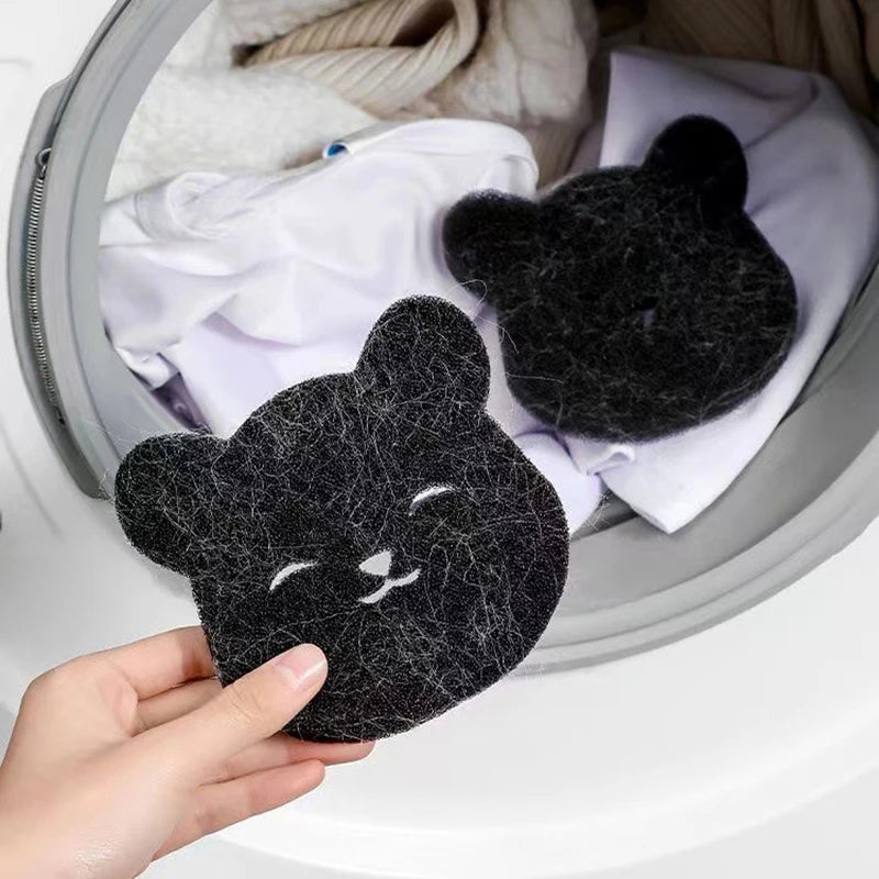 Une main tient une éponge pour enlever les poils d'animaux noire dans un panier à linge gris.