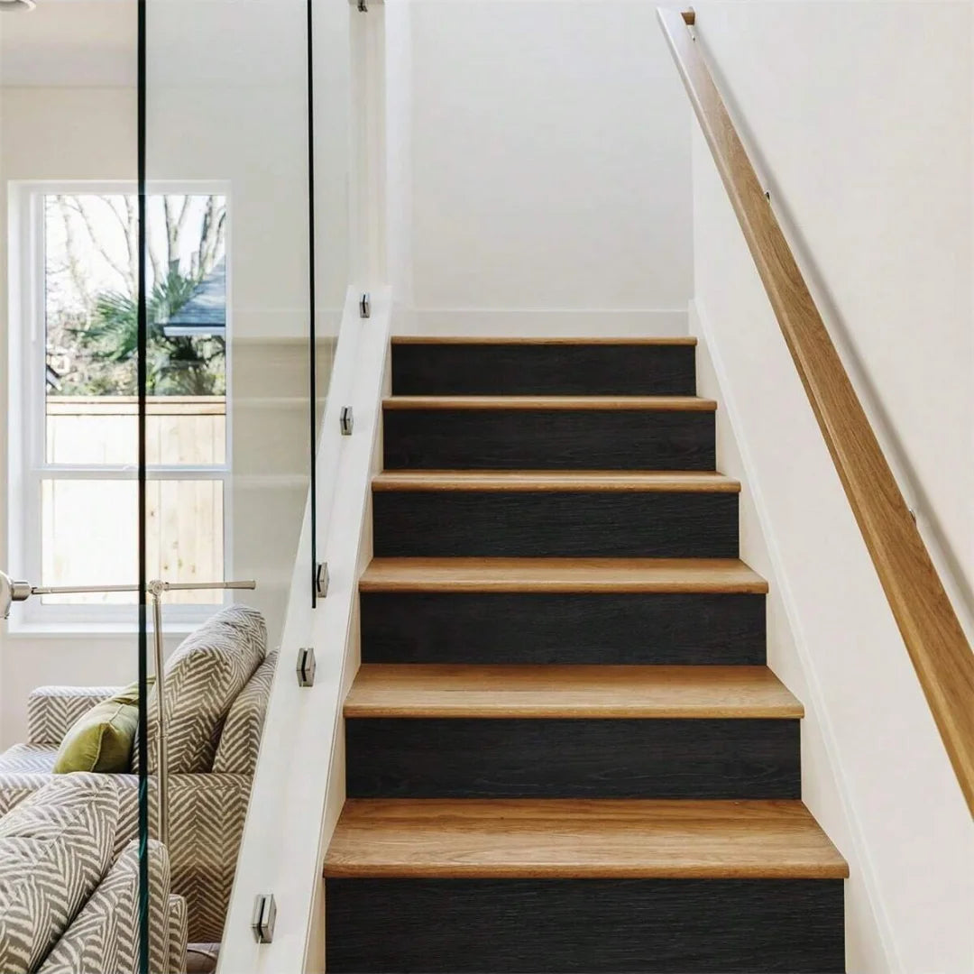 A modern interior staircase with dark wood treads and black risers, next to a glass door and window.