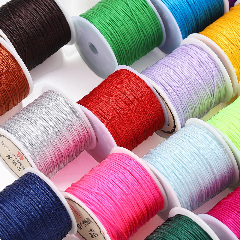 A collection of spools of multicolored 0.8mm nylon macramé cord for jewelry making.