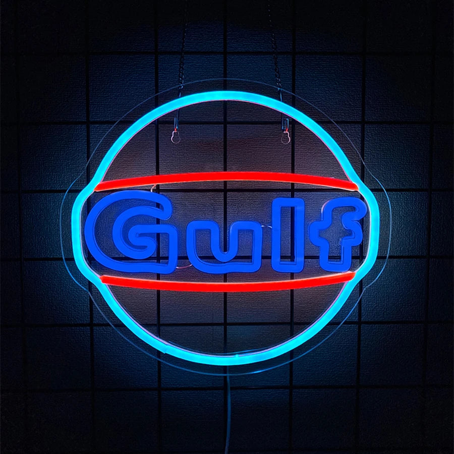 A neon sign shaped like a truck with the word Gulf illuminated in blue and red light against a dark background.