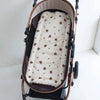 A beige and brown cartoon bear stroller cushion is shown inside a brown stroller basket.