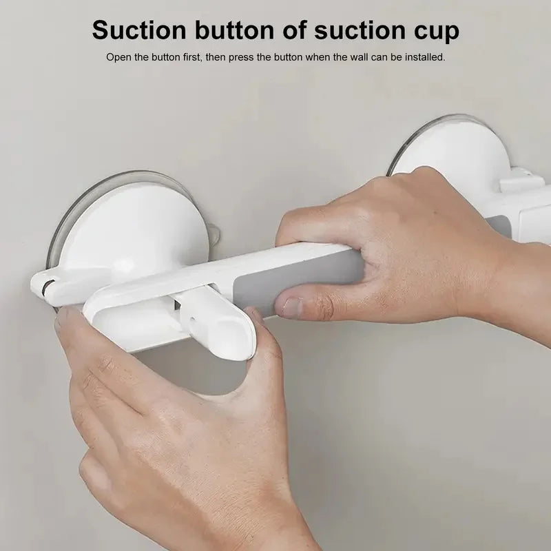 A hand is installing a suction cup grab bar onto a wall, demonstrating how to open the button before pressing it.