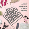 A black wire hanger is displayed on a pink background with accessories like shoes and jewelry.