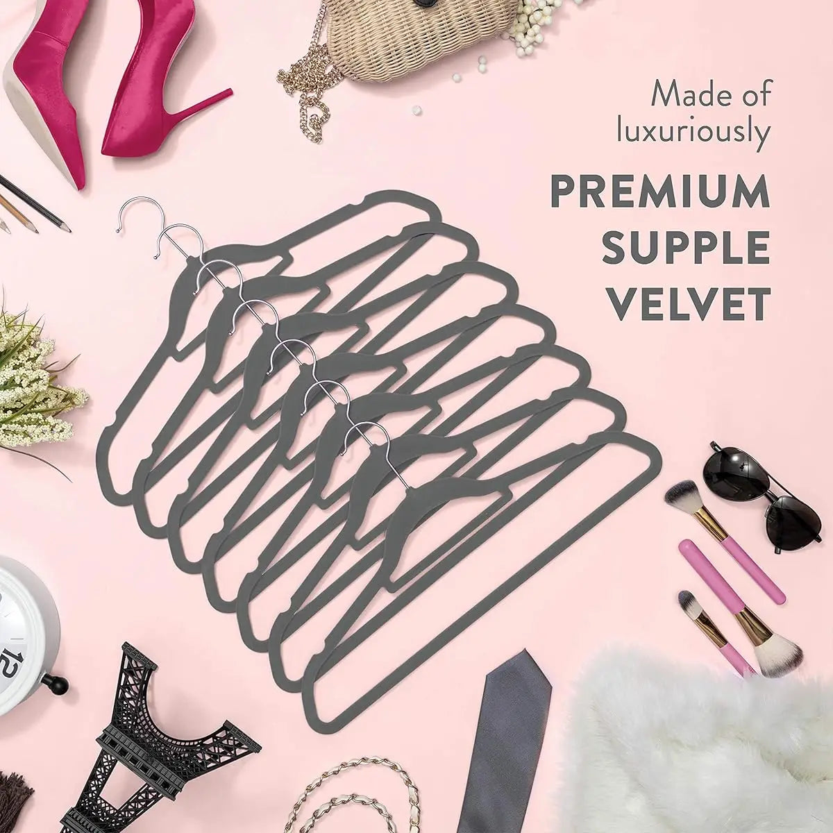 A black wire hanger is displayed on a pink background with accessories like shoes and jewelry.