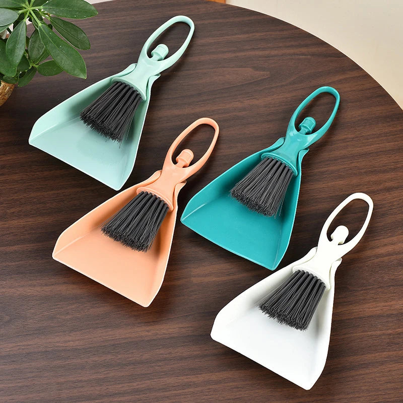 A set of three mini brooms and dustpans in teal, peach, and white for cleaning desks and keyboards.