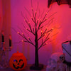 An LED Halloween birch tree with black branches and orange and purple lights set against a pink background.