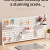 A white desktop pegboard organizer with shelves and hooks displaying various small decorative items and tools.