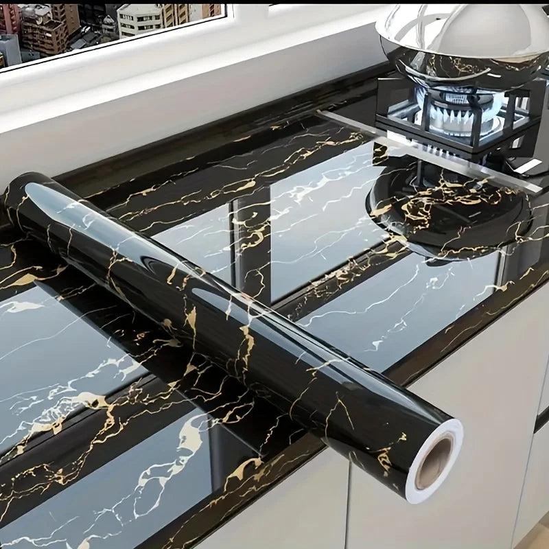 Black marble wall sticker roll with gold veining displayed on a kitchen countertop.