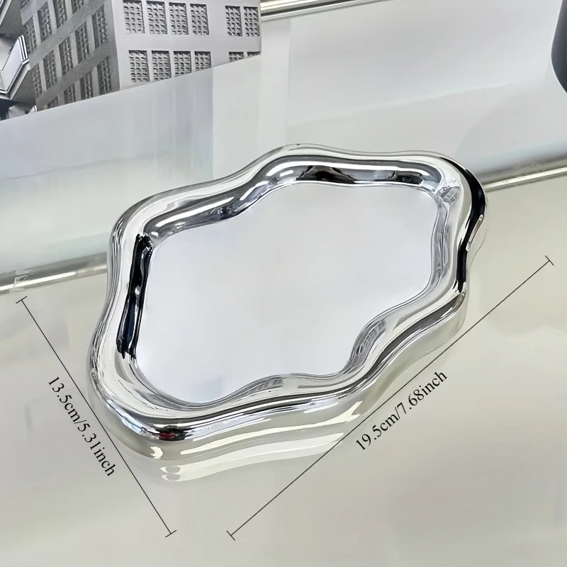 A silver cloud-shaped jewelry tray is shown on a white surface.