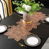 A black table set featuring ornate copper-colored floral placemats, plates, and silverware with a centerpiece of white flower