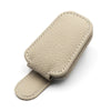 A beige magnetic leather sunglasses holder designed for car sun visors.