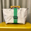 A white reusable elastic luggage strap with a green strap and black buckle resting on a yellow surface.