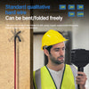A man in a yellow safety vest is holding an industrial endoscope probe against a textured wall.