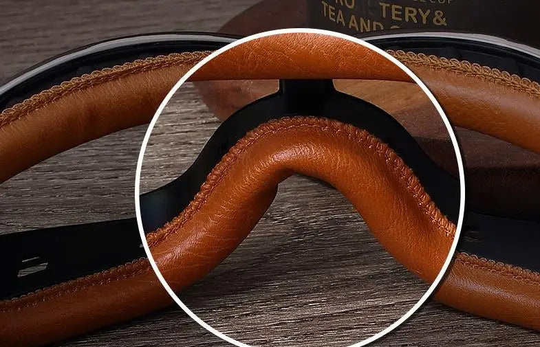 Close-up view of the brown leather foldable goggles showing the curved frame and padding.