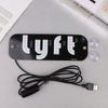 A black USB-powered LED taxi sign with letters LYFT mounted on a white background and connected by a black wire.