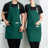 A woman wearing a dark green waterproof canvas chef apron standing next to a man.