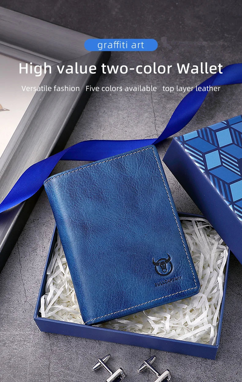 A dark blue leather wallet is shown inside a box with shredded paper, next to a blue ribbon and some metal keys.