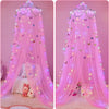 Pink sheer bed curtain draped like a dome mosquito net with sparkling LED lights and soft bedding accessories