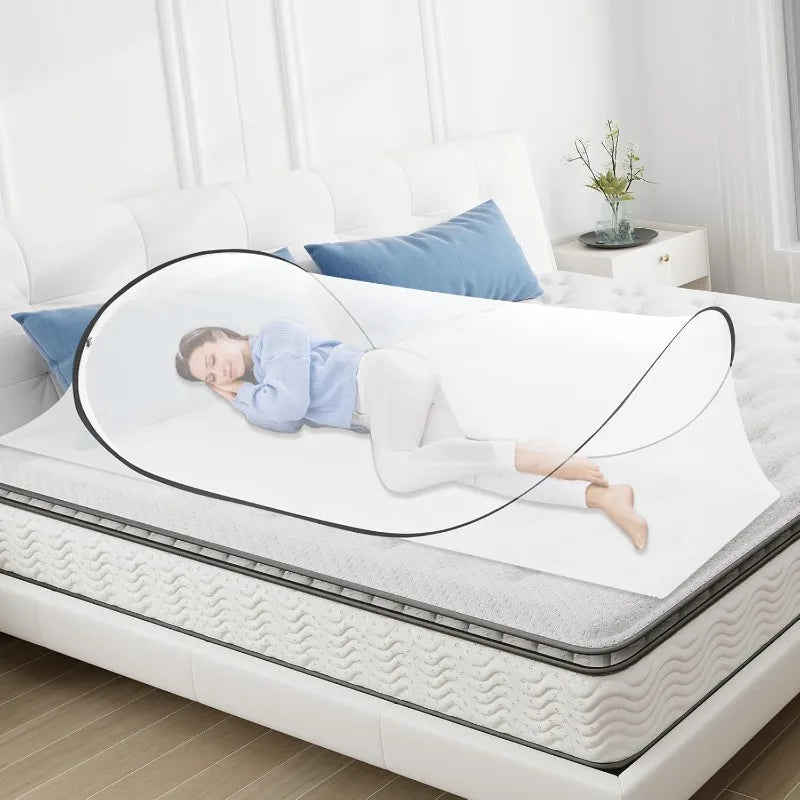 A transparent dome-shaped mosquito net is shown resting on a white bed, illustrating its pop-up design.