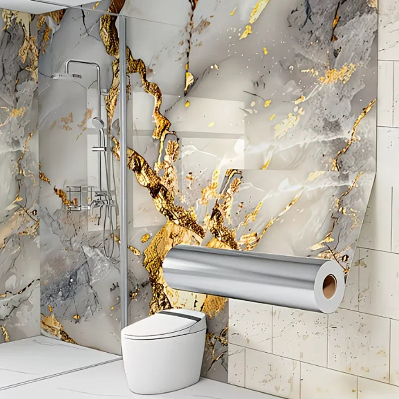 A toilet is mounted on a marble wall featuring gold leaf accents and gray marble patterns.